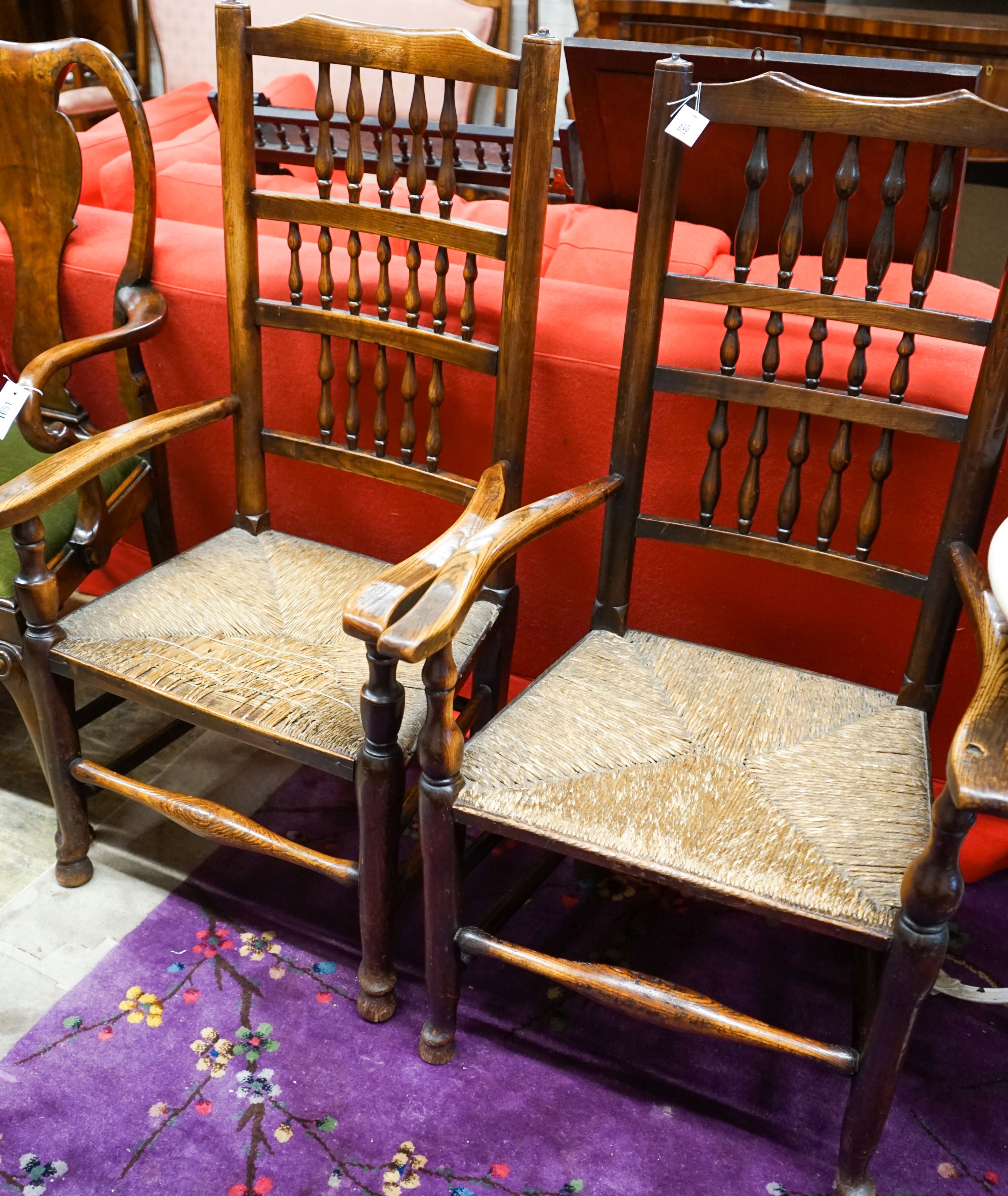 A near pair of Lancashire ash and elm rush seat spindle back elbow chairs